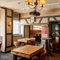 Interior dining area of a pub with a TV, a fireplace, a pool table and a gambling machine.