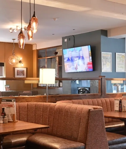 The interior restaurant seating area with seating booths and TV at The Quays.
