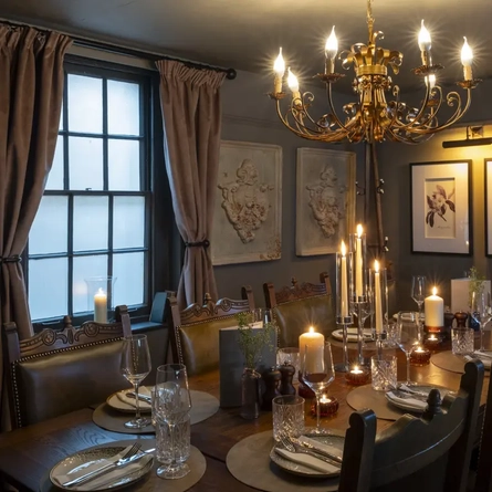 Function room with large table set up for a meal with a chandelier and a large window