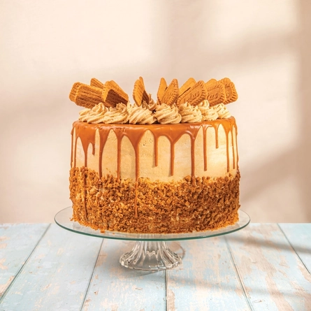 A whole Biscoff cake on a glass cake stand.