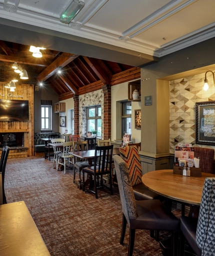 Interior dining area of a pub with a TV and a fireplace.