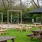 The exterior beer garden seating area and children's play area at The Hussey Arms in Brownhills, with wooden picnic tables, shade umbrellas, and obstacle course.