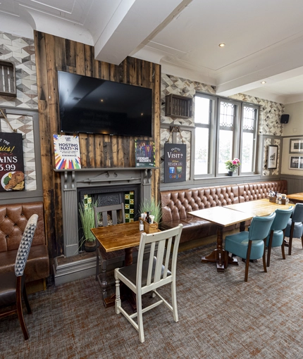 Interior dining area of a pub with a TV and a fireplace.