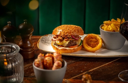 A plated burger with a range of sides on a wooden table.