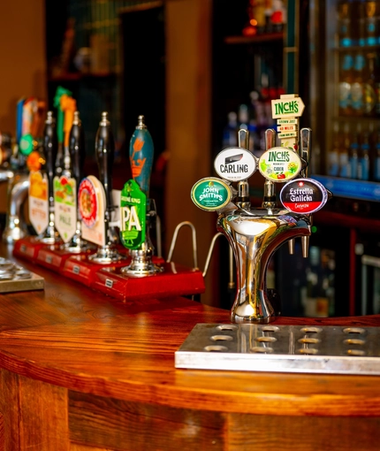 A close up view of the beer taps and golden drinks trays on the bar inside The Windmill Inn.