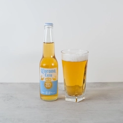 An advertising image of a bottle and glass of 0% Corona Cero Lager.