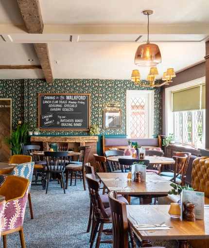 The interior restaurant seating area at The Walkford, with upholstered booth seating, leaded windows, and a fireplace.