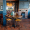 An image of the interior restaurant seating area with tables, chairs, brick log burner fireplace and tiled flooring at The Spice Island.