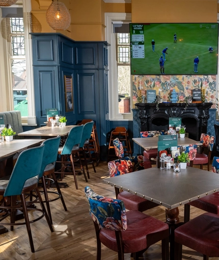 The interior restaurant seating area at The Victoria in Lytham St Annes, with an ornate black fireplace and a TV on the wall.
