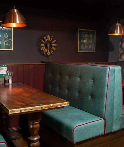 An interior restaurant seating area at The Ship; with upholstered booth seats, and framed artwork on the wall.