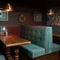 An interior restaurant seating area at The Ship; with upholstered booth seats, and framed artwork on the wall.