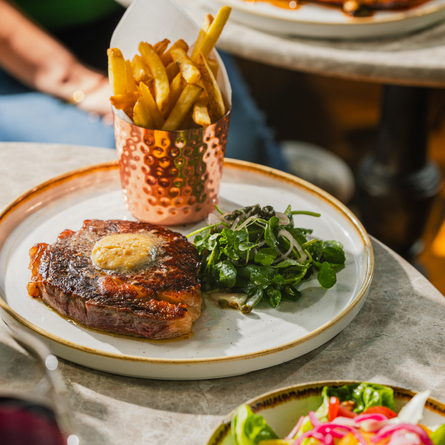 An advertising image showing a plated steak dish sat on a table at a Crafted venue.