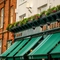 A close up view of the exterior facade and signage of The Globe in Marylebone; with large green awnings, and flower boxes at the upper floor.