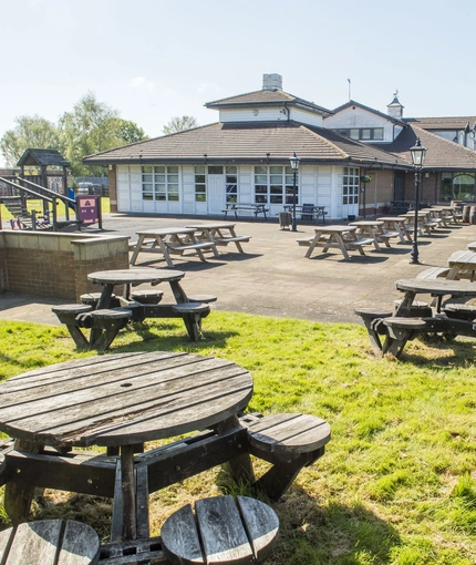 Exterior beer garden of a pub with a seating area and a play area.