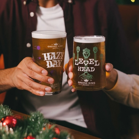 An image of a pint of Hazy Day and a pint of Level Head being held within the interior seating area at an Urban Core venue.