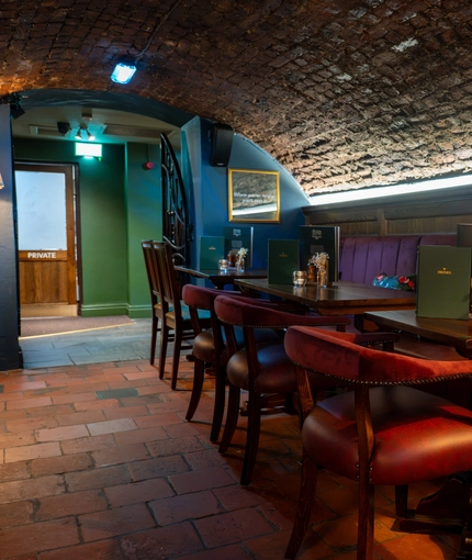 The interior restaurant seating area with tables, chairs, cushioned seating, arched brick ceiling and tiled flooring at The Watergates Bar.