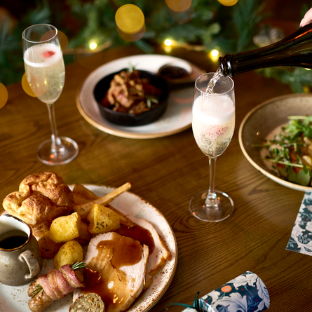 An image of drinks being poured with 3 festive dishes sat on a table within the interior restaurant seating area at a Chef & Brewer venue.