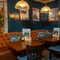 The interior restaurant seating area of the Cock & Pye, with upholstered booth seating and framed artwork on the wall.