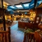 The central bar area inside the Old School House, with TVs above the bar, large sky lights in the ceiling, and restaurant seating areas on the lower and upper floors, with a balcony overlooking the bar.