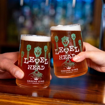 The hands of two people holding a pint of Level Head each on a bar.