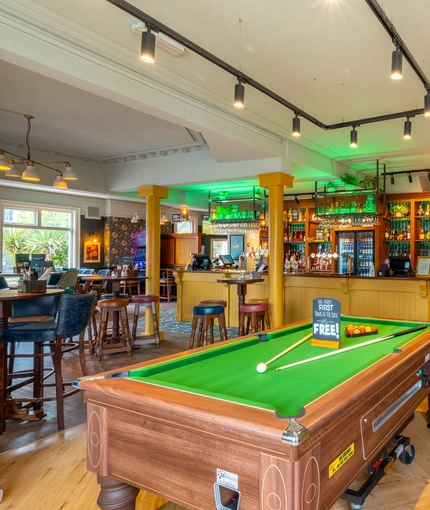 The bar, interior restaurant seating area, and games area of the Malvern Tavern in Shirley, with a pool table, gaming machines, and a TV on the wall.