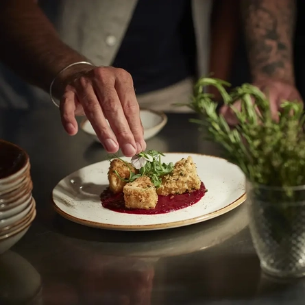 A hand adding a garnish to some cheese bites.