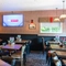 The interior restaurant seating area at The Bramford Arms in Woodsetton; with a long, upholstered booth seat along one side of the room, and a TV on the wall.