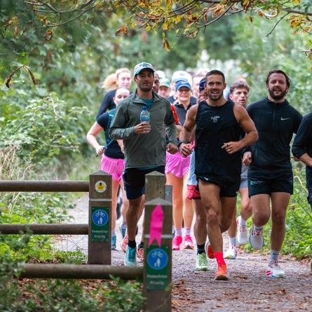An image of a crowd of people running in a group through woodland.