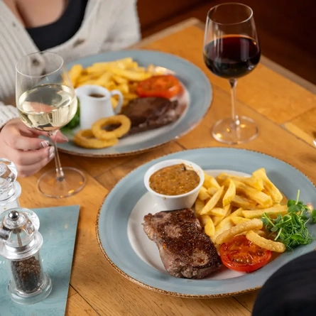 Two main meals and glasses of wine on a table