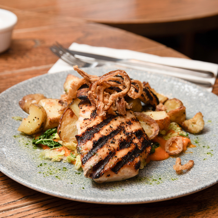 A plated dish sat on a wooden table in the exterior of The Blue Cap.