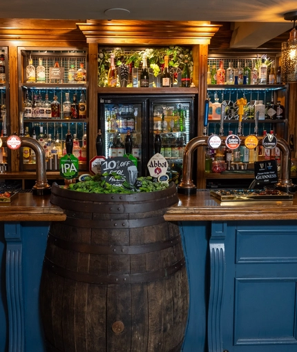 A close up view of the blue, wood panelled bar of The Royal Oak, with a large beer barrel built into the counter.