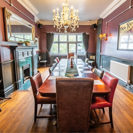 The interior of one of the function rooms with tiled fireplace and large table laid out with pens and paper at The Vine.