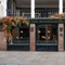 The exterior facade of the venue with historical information signage and Autumnal hanging floral decor at The Watergates Bar.
