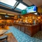 The bar area inside the Old School House, with TVs on the wall above the bar, large sky lights in the ceiling, and views of the restaurant seating areas on the upper and lower floors.