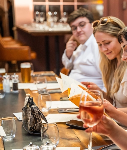 A group of people enjoying drinks and viewing the menu within the interior restaurant seating area during The Durell Arms launch party.