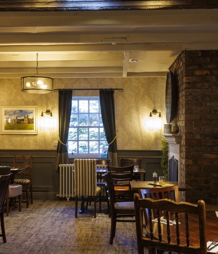Interior dining area of a pub with a fireplace.