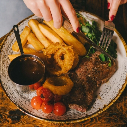 A close up lifestyle image of a Mother's Day Steak and chips main dish sat on a table within the interior restaurant seating area at a Heritage venue.