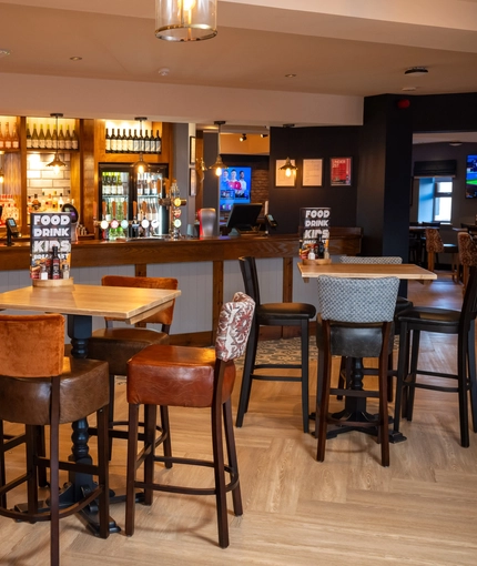 The bar and interior restaurant seating area of The Parsonage in Leigh, with TVs on the walls.