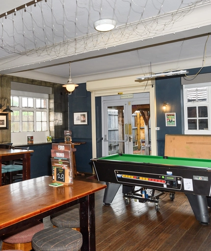 Interior dining area of a pub with a pool table and a TV.