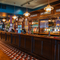 A close up view of the wood panelled bar at the Scholars Arms in Southampton; with patterned tile flooring in front of the counter, and a TV on the wall.