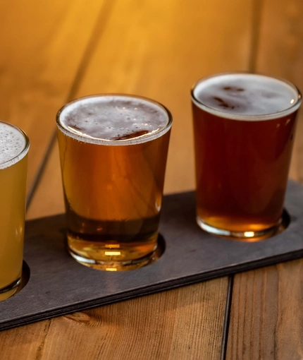 A product image of 3 beers served in glasses on a board within the interior of Williams Ale & Cider House.