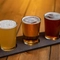 A product image of 3 beers served in glasses on a board within the interior of Williams Ale & Cider House.