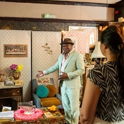 A historian 'Tony Fairweather' showing Greene King staff a staged Windrush Front Room during Black history month.