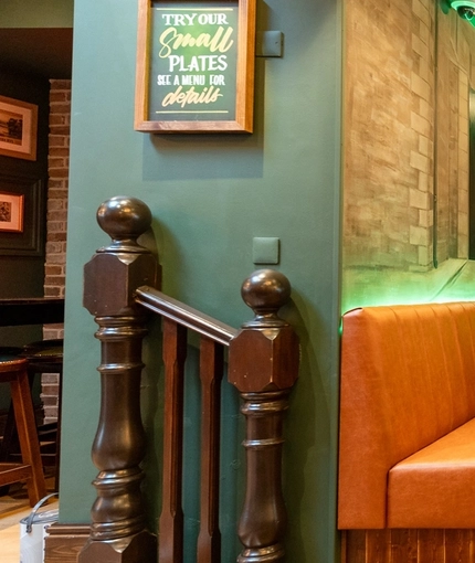 An interior seating area at Molly Malones, with upholstered seating, wooden tables, and pub gaming machines.