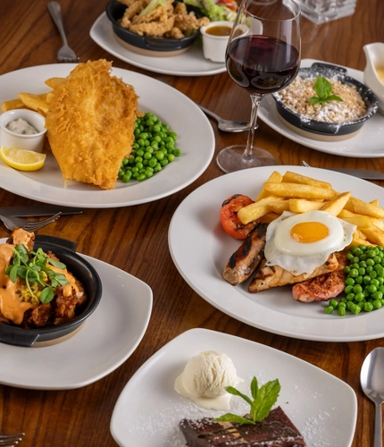 plates of food sitting on a wooden table of a pub