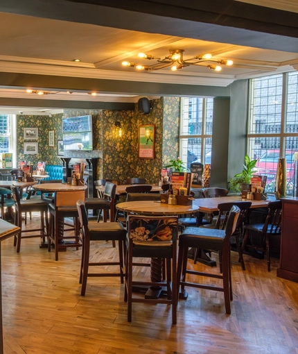 The interior bar and restaurant seating area with TV and fireplace at The Hare & Hounds.