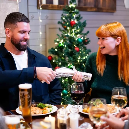Two people pulling a Christmas cracker