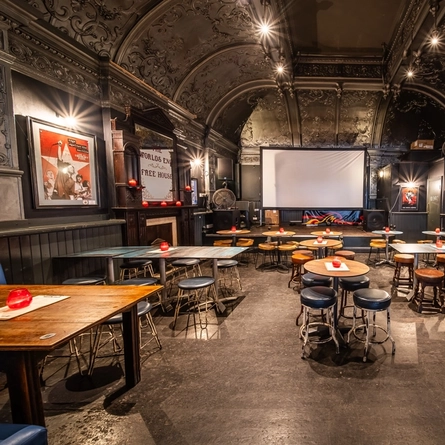 The interior seating area within the function room with live event stage area, projector screen and ornate ceiling at The Worlds End.