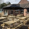 The exterior beer garden seating area at the Devonshire Arms in Sheffield, with wooden picnic tables, shade umbrellas, and string lights.