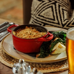 An advertising image of a Pie Choice dish and a pint of beer within the interior restaurant and seating area at The Foundry Bell.